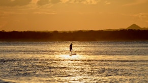 man and woman walking on beach during sunset