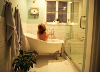 woman in bathtub near white bathtub