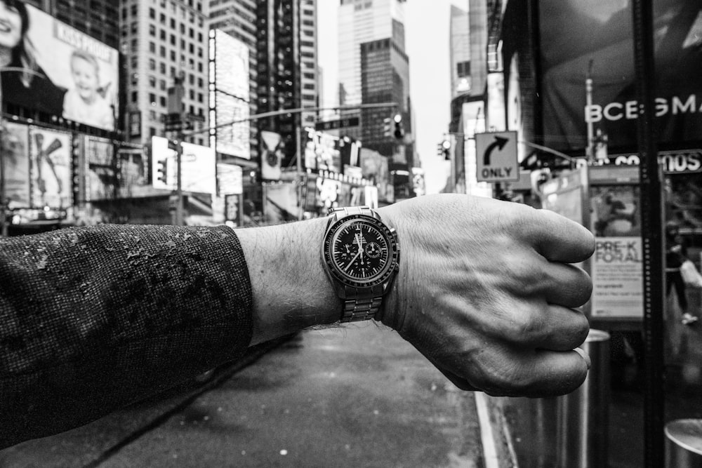 grayscale photo of person wearing round black analog watch