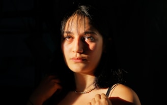 Shadowy profile of a woman's neck illuminated by a single warm light, with a hint of champagne gold glow nearby.