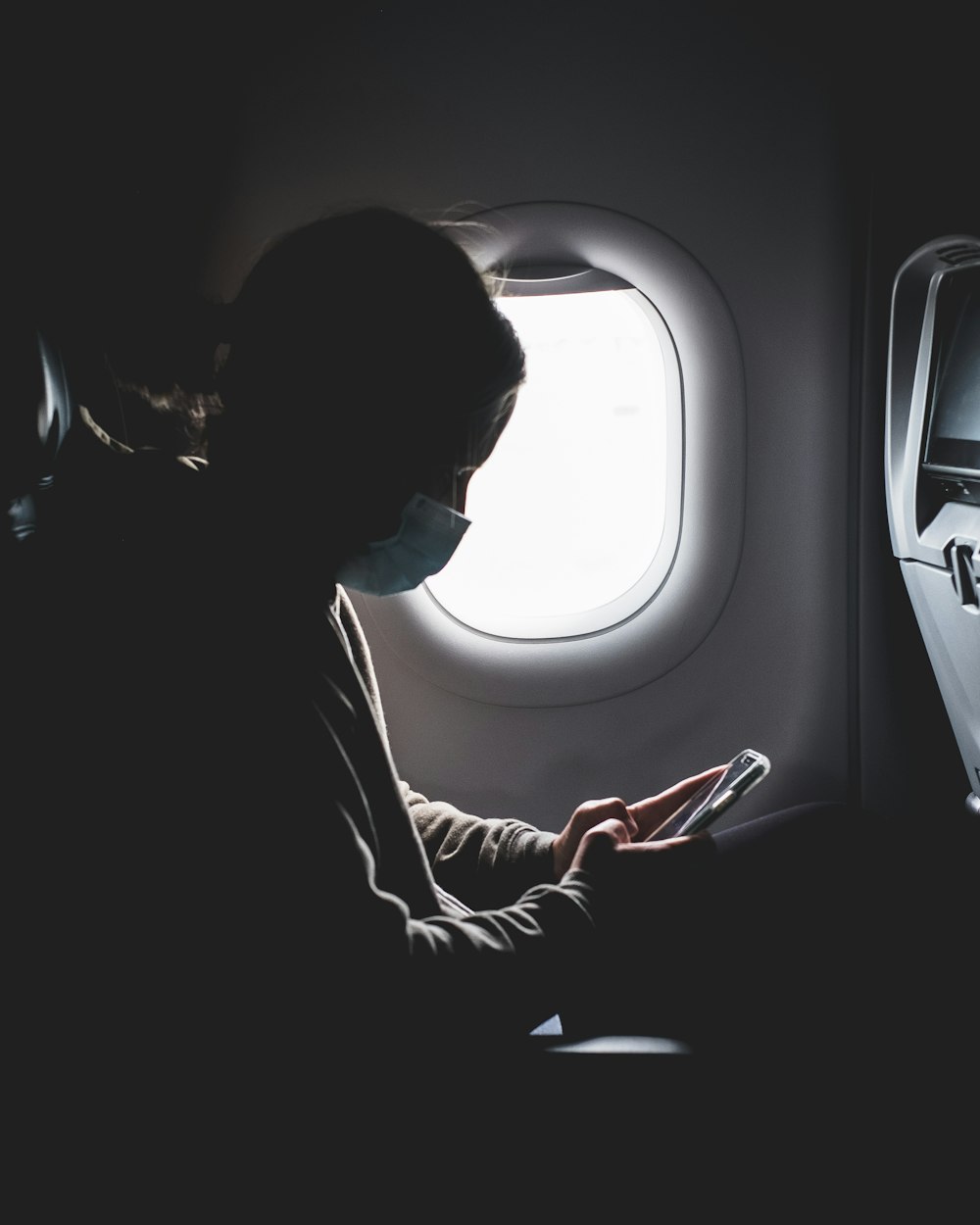 mulher na camisa preta da manga comprida sentada no assento do avião