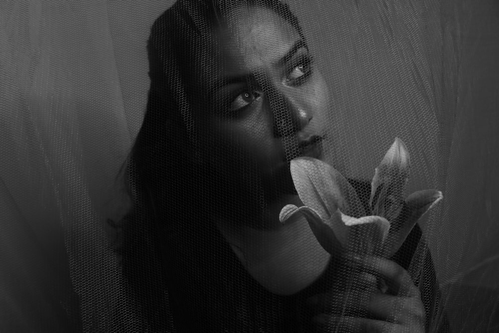 woman holding white flower in grayscale photography