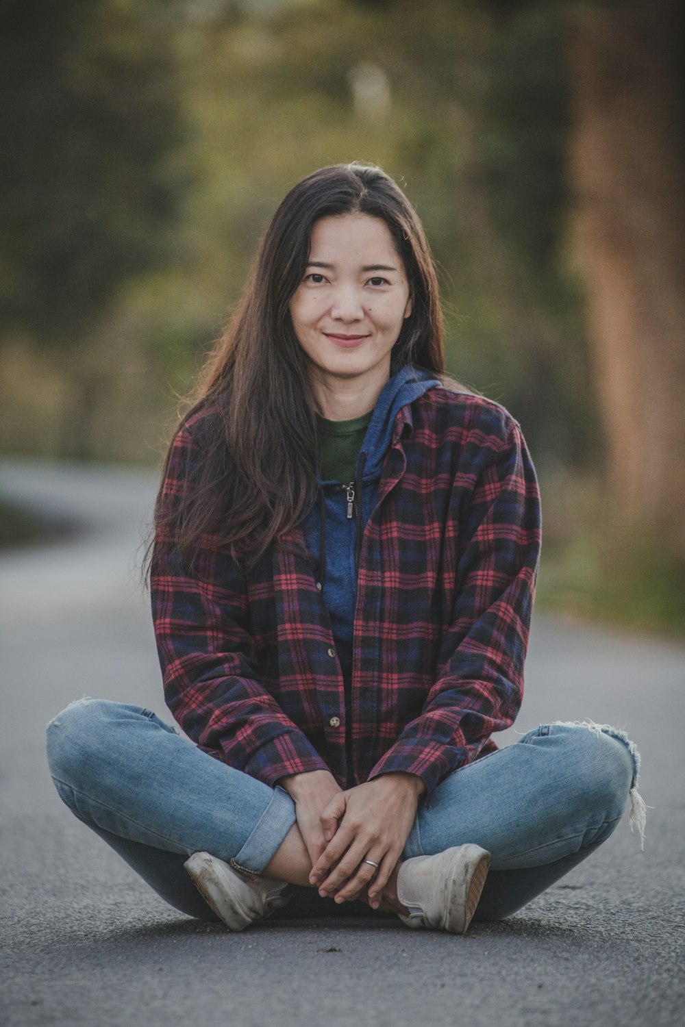 woman in red and black plaid dress shirt and blue denim jeans sitting on gray rock