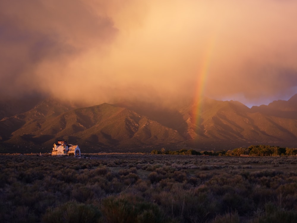 white and brown house on green grass field near mountain during daytime