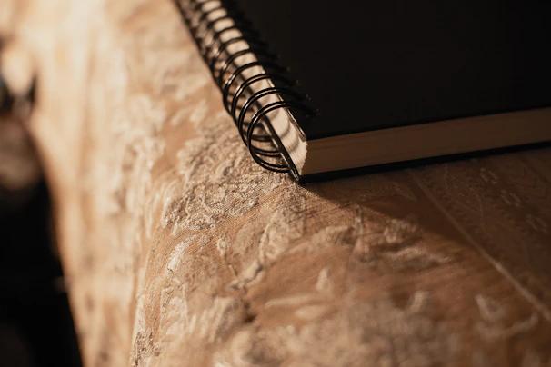 A close-up of a notebook filled with business plans and sketches, amber light casting soft shadows.