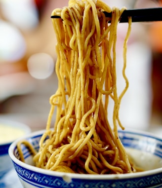 yellow pasta on blue and white ceramic bowl