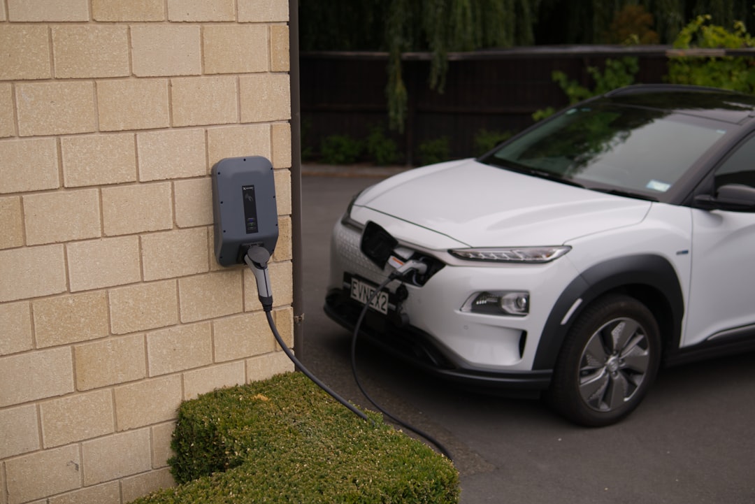 black car parked beside brown brick wall, Hyundai Kona charging at Evnex charging station