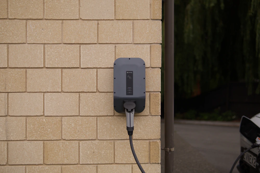Wall-mounted EV charger on a block wall beside the driveway