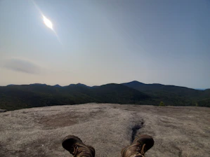 Close-up of durable mountaineering boots resting on a rocky mountain trail at sunrise.