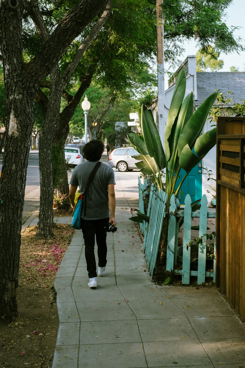 man in gray t-shirt and blue denim jeans walking on sidewalk during daytime