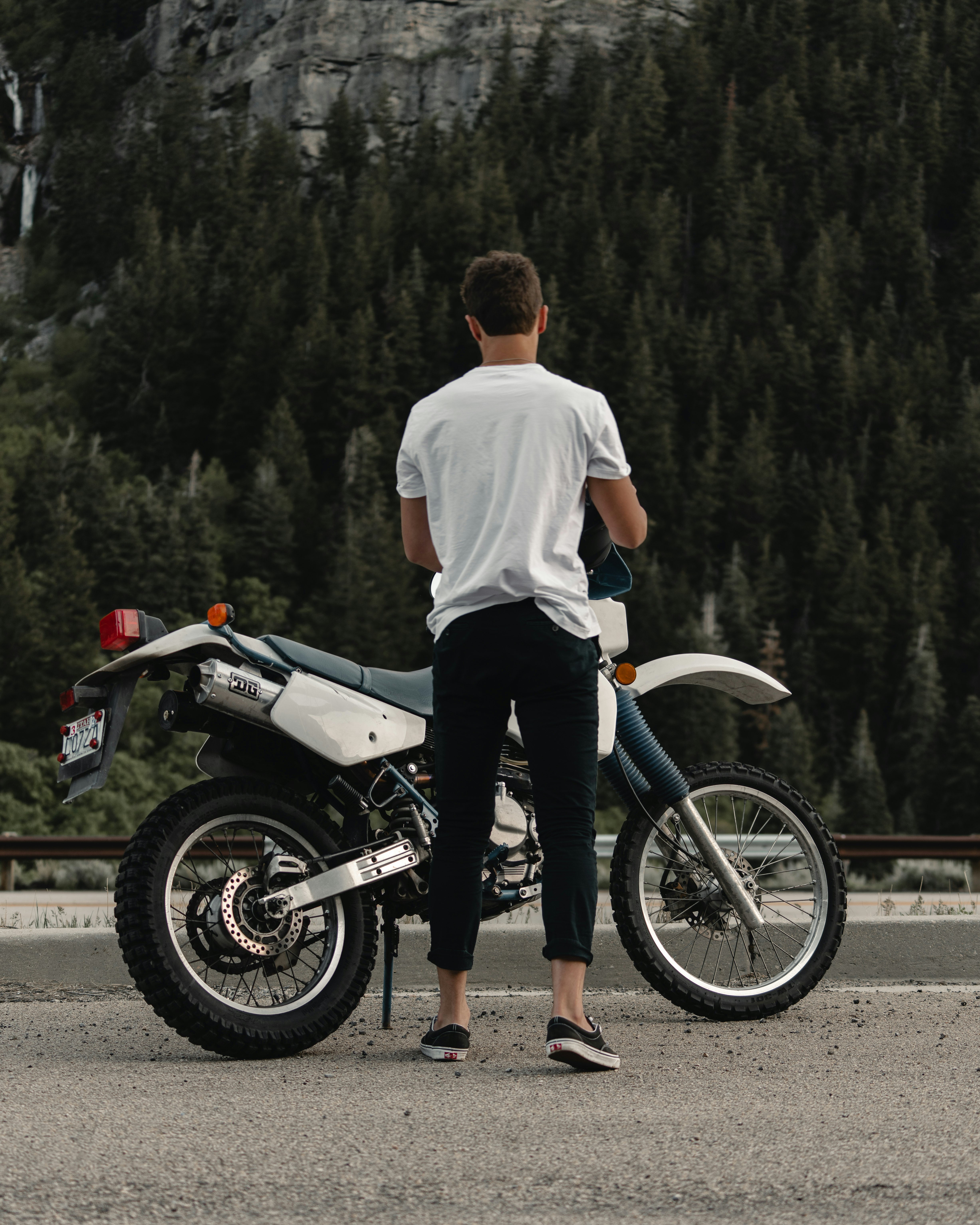 man in white shirt and black pants riding black and white sports bike