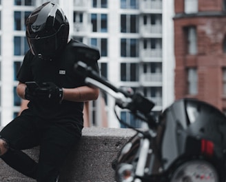 man in black jacket and gray pants wearing black helmet riding motorcycle during daytime
