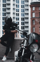 man in black jacket and gray pants wearing black helmet riding motorcycle during daytime