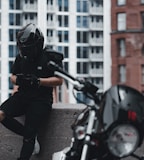 man in black jacket and gray pants wearing black helmet riding motorcycle during daytime