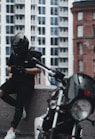 man in black jacket and gray pants wearing black helmet riding motorcycle during daytime