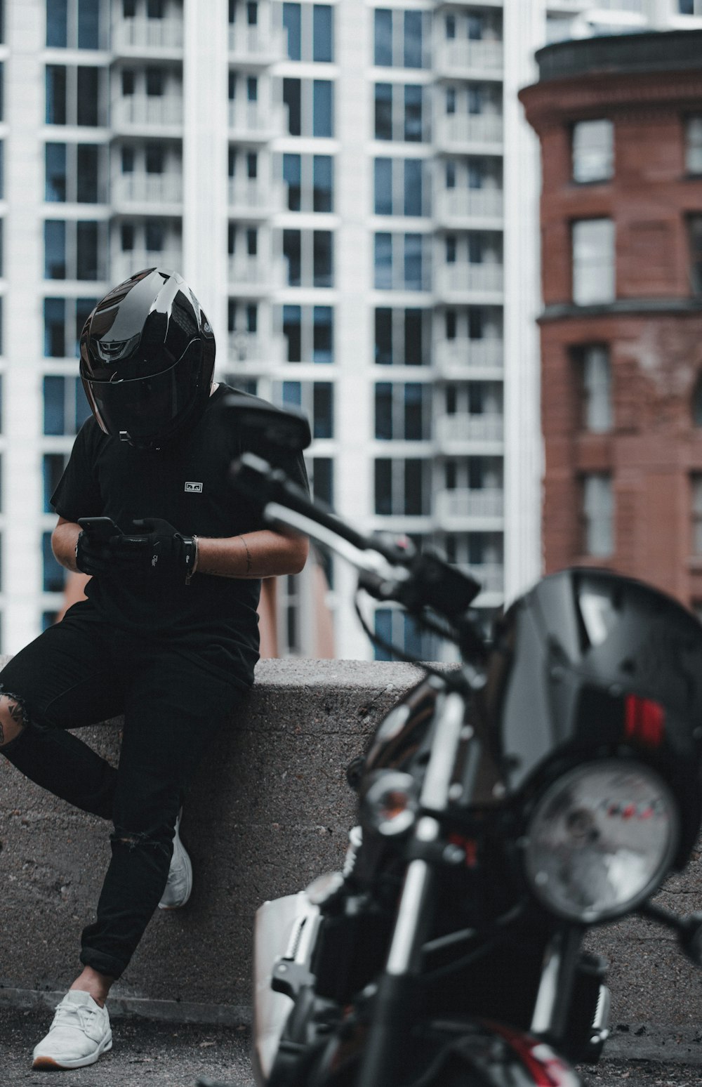 Mann in schwarzer Jacke und grauer Hose mit schwarzem Helm beim Motorradfahren tagsüber