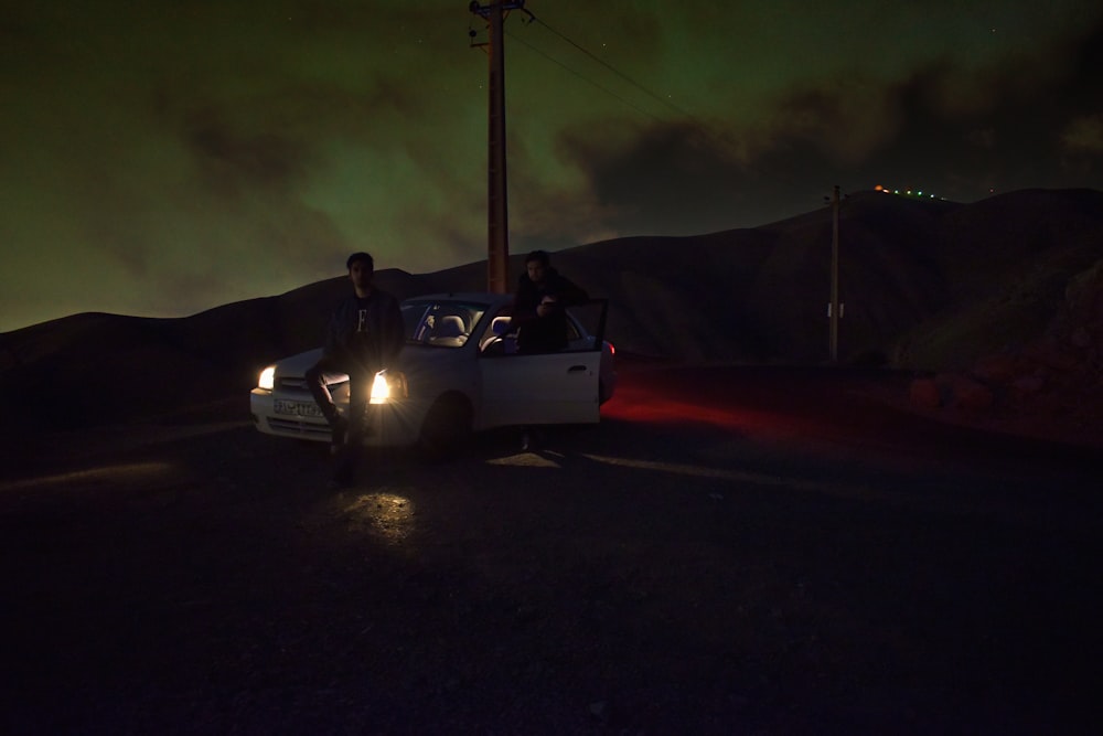 man in black jacket riding white coupe during night time