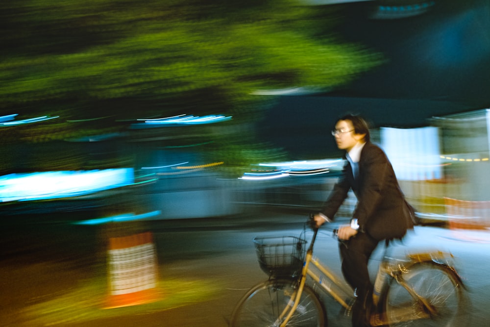 man in black suit riding bicycle on road during night time