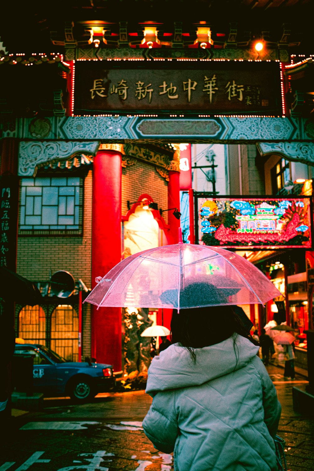 personne en veste grise tenant un parapluie rose