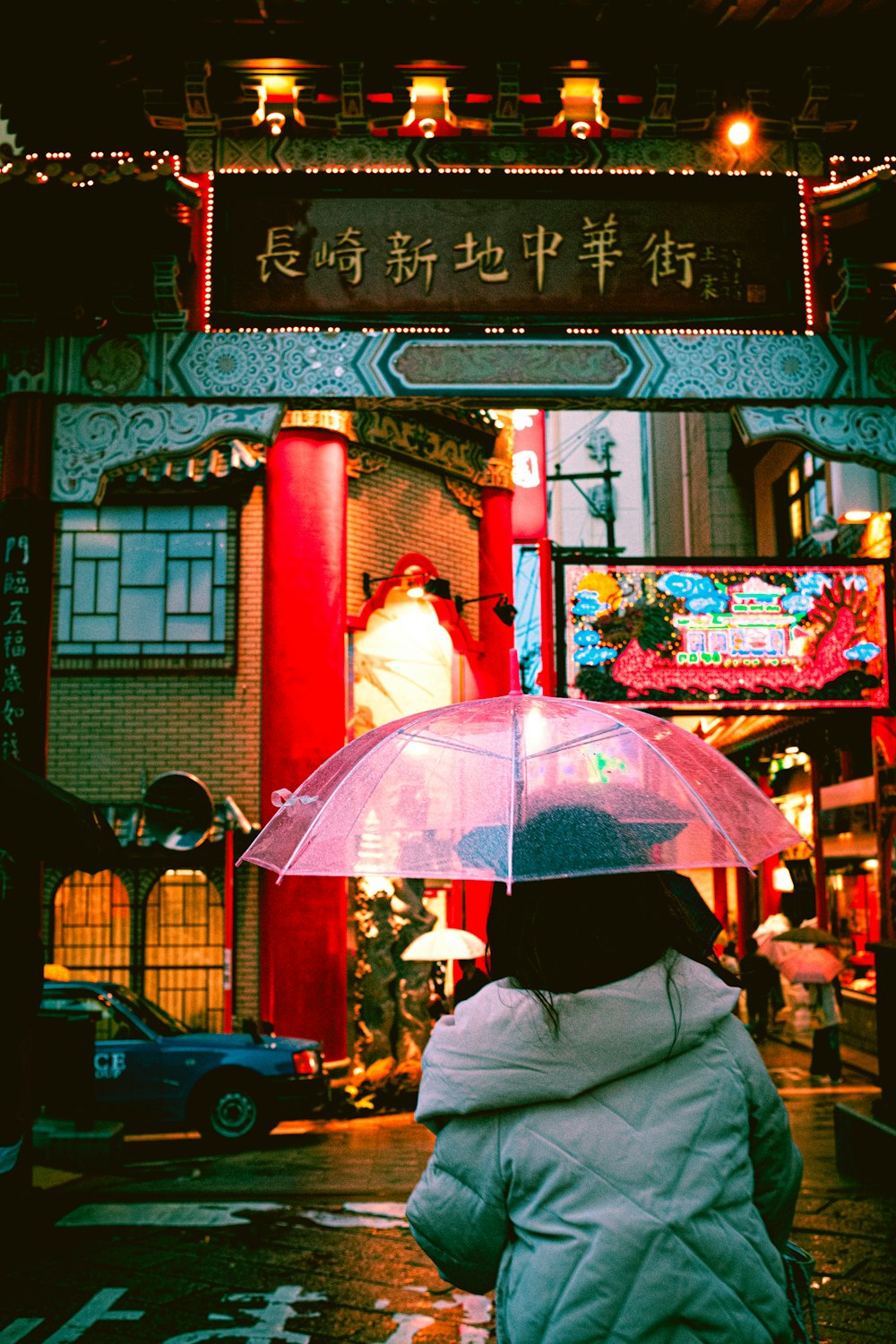 person in gray jacket holding pink umbrella