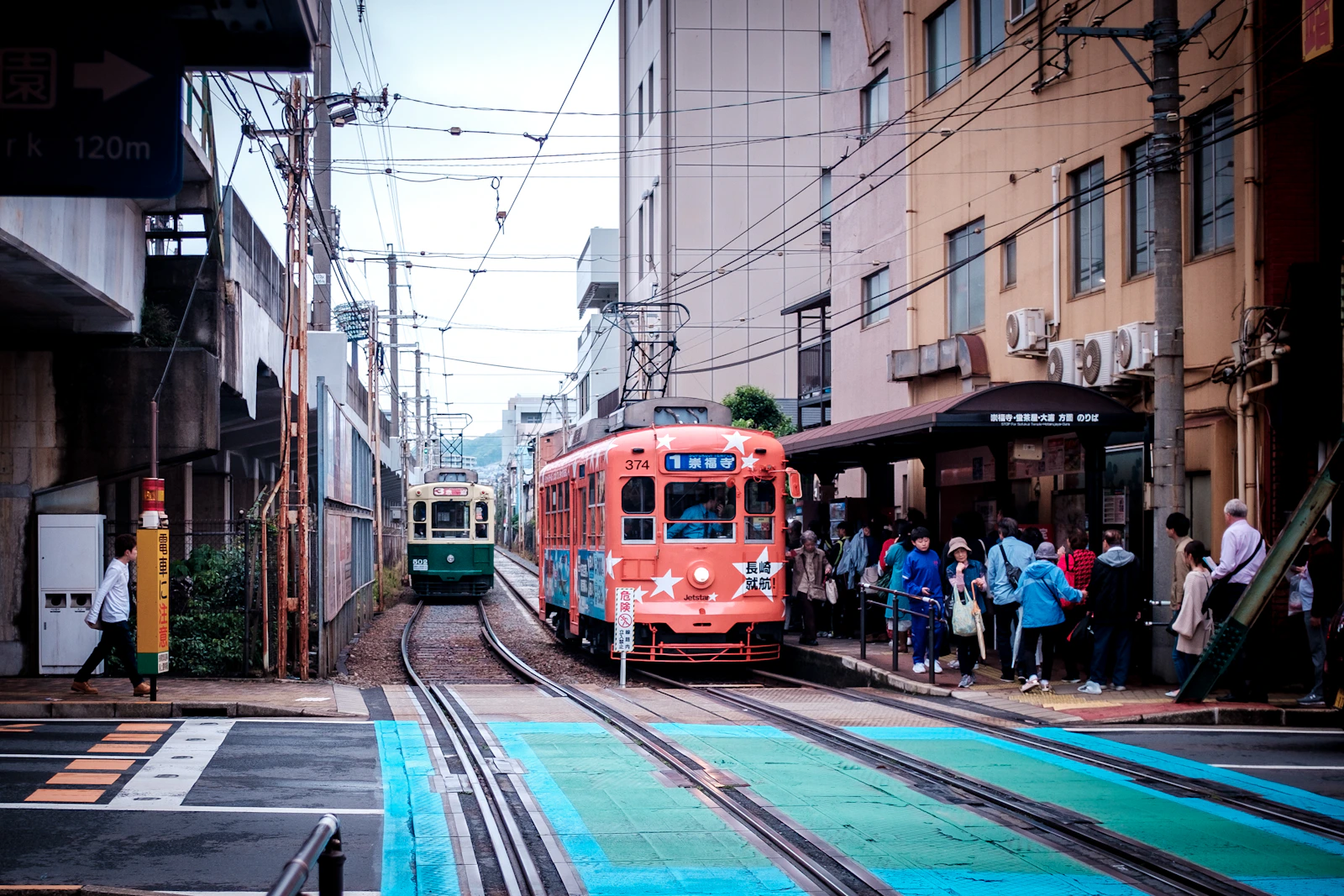 Red and white Nagasaki streetcar travelling along a city street in Nagasaki, Japan