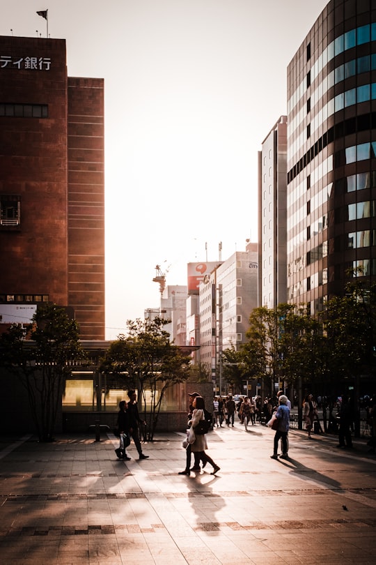 people walking on sidewalk near high rise buildings during daytime in Fukuoka Japan