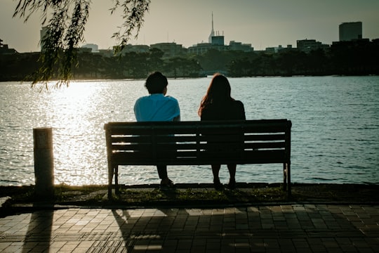 2 person sitting on bench near body of water during daytime in Ōhorikōen Japan