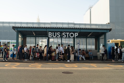 A busy bus station with people waiting for eco-friendly buses.