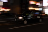 A sleek modern taxi driving through a city street at dusk.