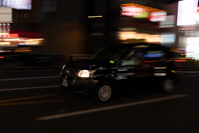 A sleek taxi driving through the city streets at night.