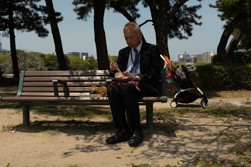 man in black jacket sitting on brown wooden bench