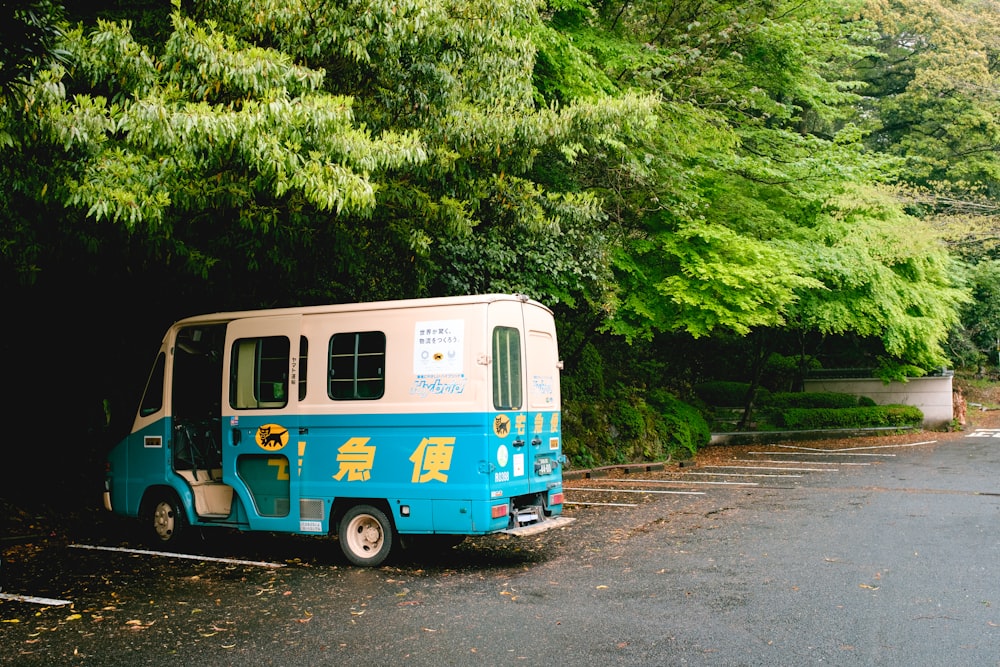 blue and white van parked beside green trees during daytime