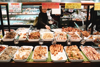 man in white long sleeve shirt standing in front of food display