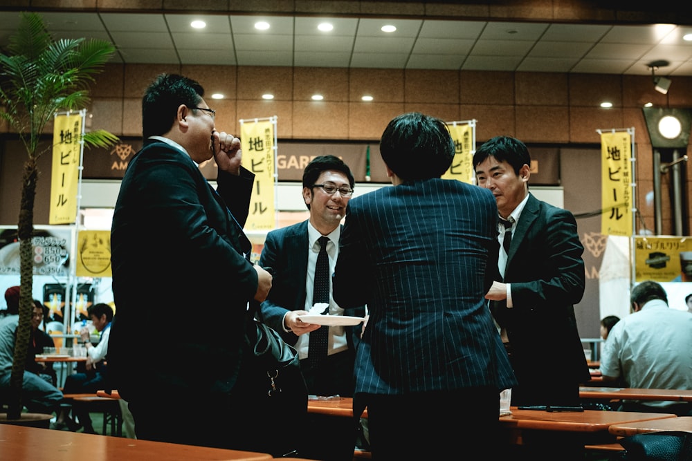 group of people standing in front of brown wooden table