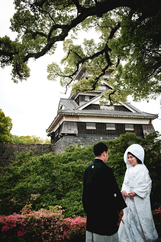 man in black suit standing beside woman in white hijab in Kato Shrine Japan