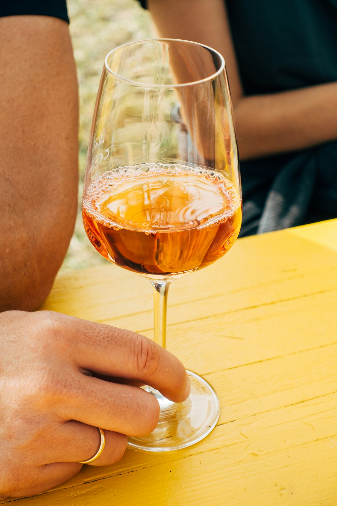 person holding clear wine glass with brown liquid