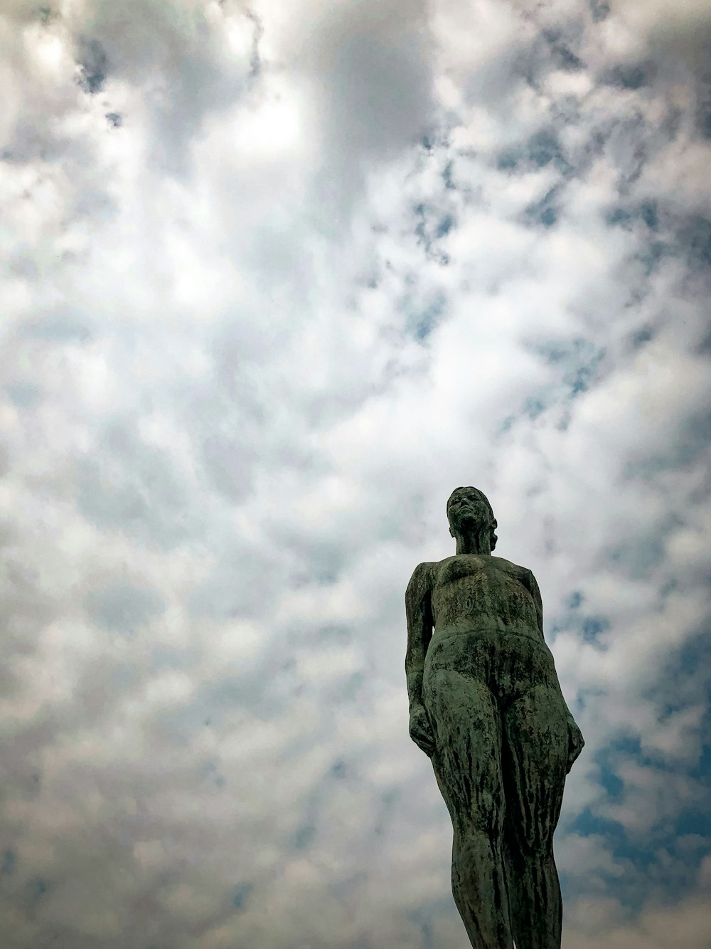 man statue under white clouds during daytime