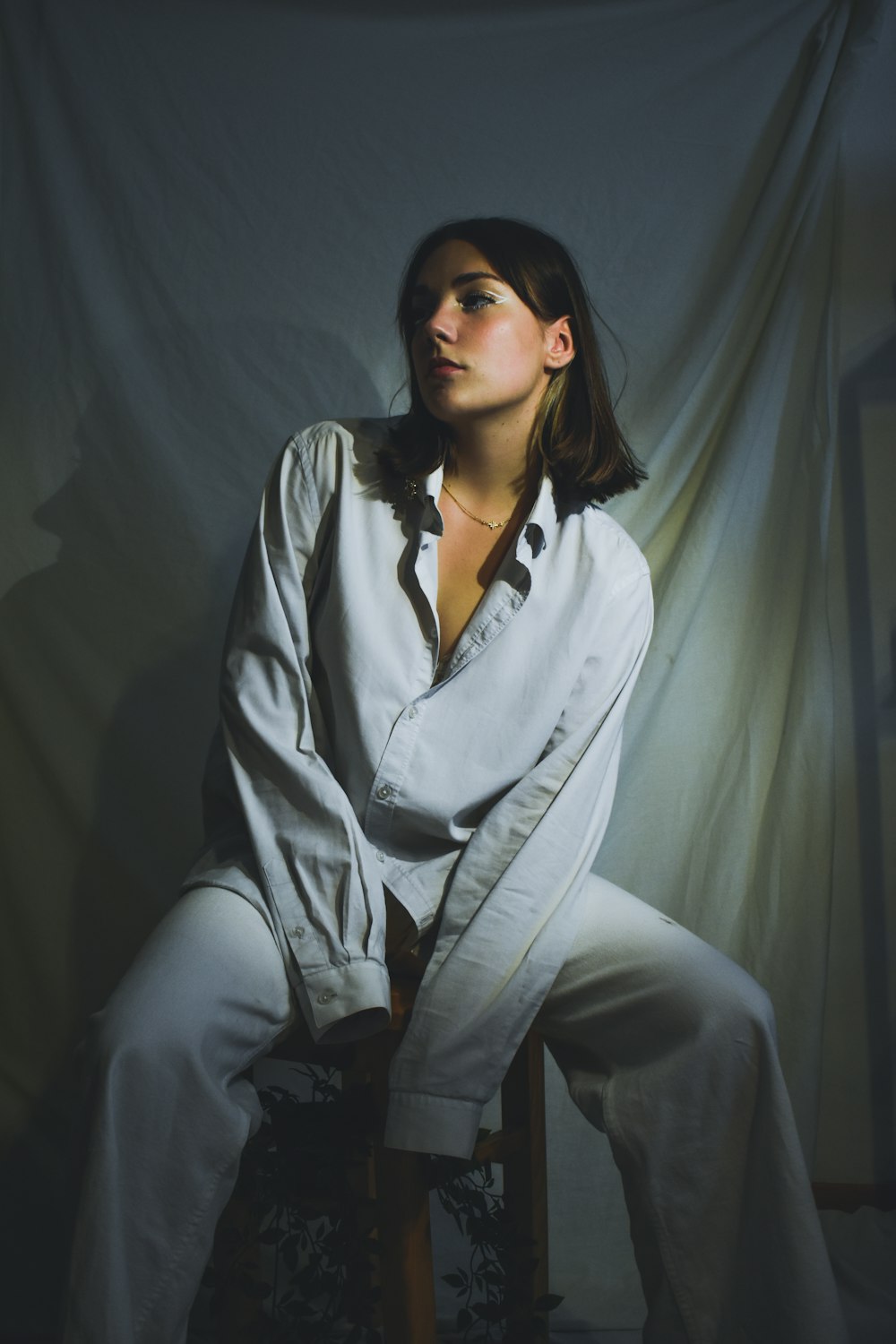 woman in white button up long sleeve shirt and black pants sitting on gray textile