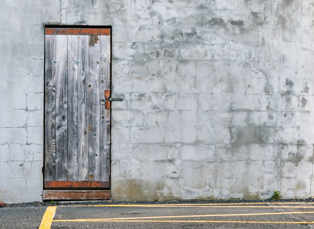 brown wooden door beside gray concrete wall