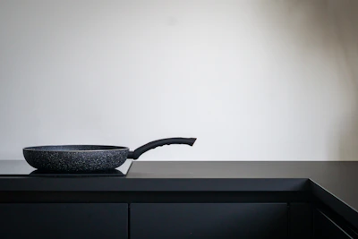 Antiaderente pan with ergonomic handle resting on a marble countertop.