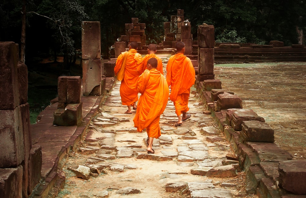 주황색 가운을 입은 남자가 낮에 회색 콘크리트 통로를 걷고 있습니다.
