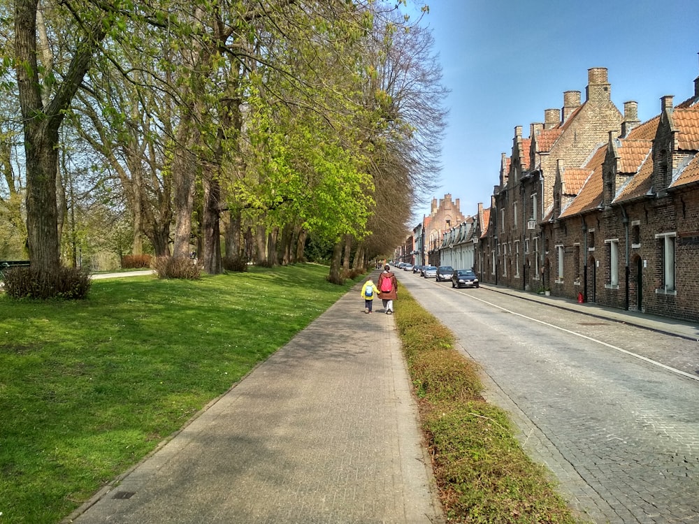 people walking on sidewalk near brown concrete building during daytime