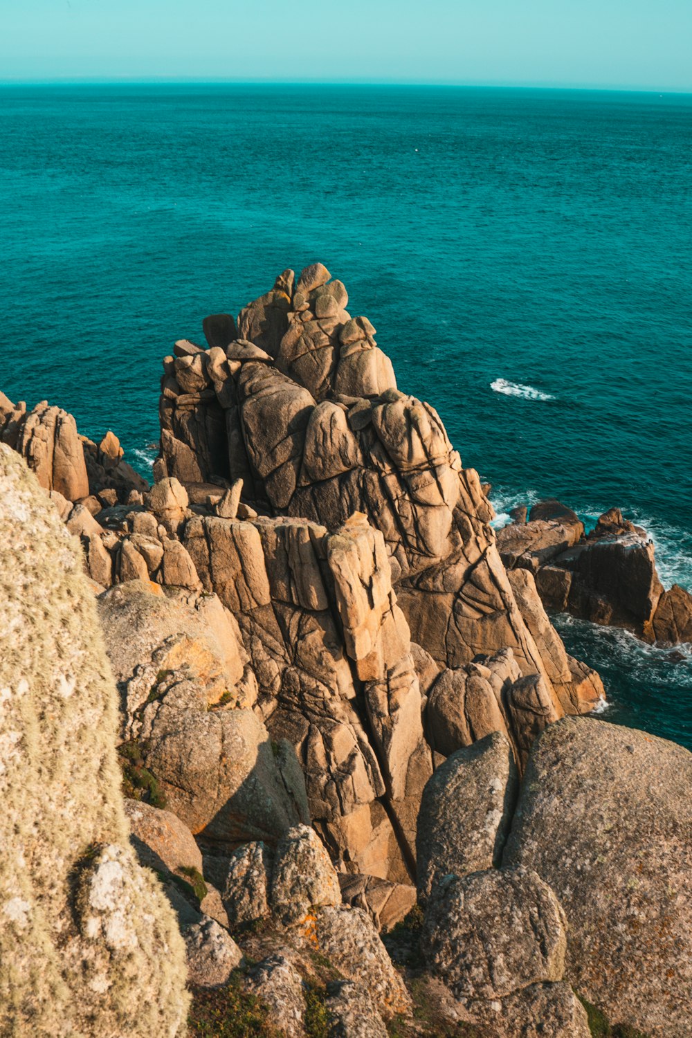 montanha rochosa marrom ao lado do mar azul durante o dia