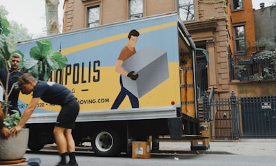 woman in blue shorts and black boots standing beside yellow and white truck during daytime