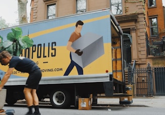 woman in blue shorts and black boots standing beside yellow and white truck during daytime