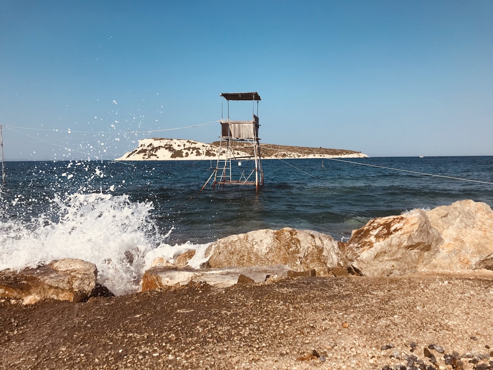 brown wooden lifeguard house on brown rock near sea during daytime