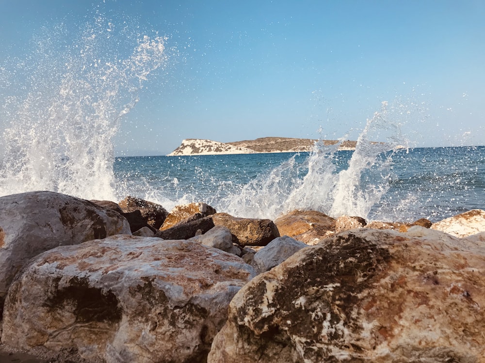 Rivage rocheux brun avec les vagues de l’océan s’écrasant sur le rivage pendant la journée