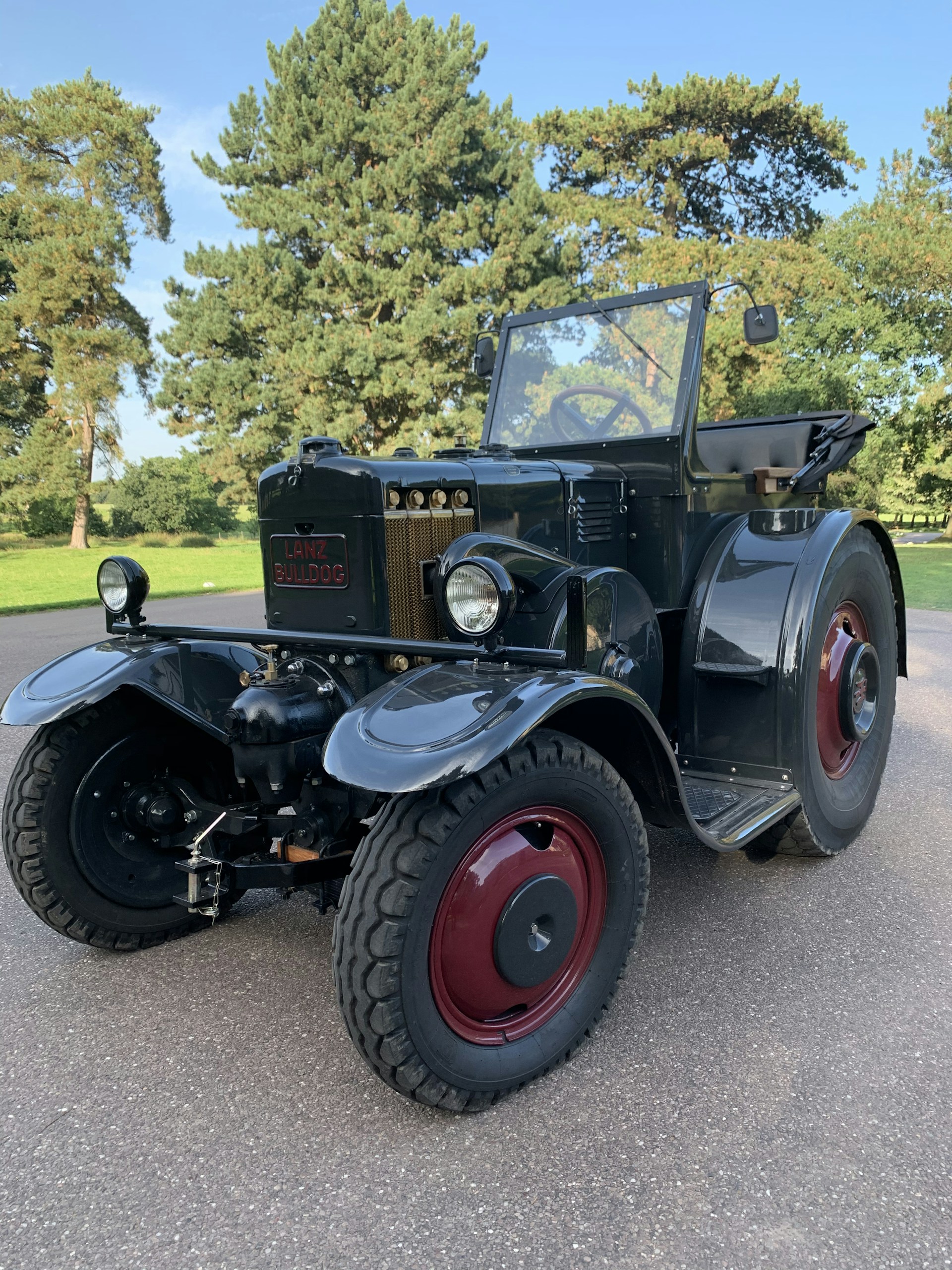 A classic green Hürlimann tractor parked beside a rustic barn, highlighting its sturdy build and timeless charm.