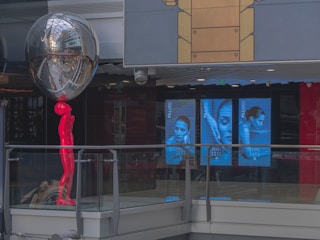 A marble statue pointing towards vibrant digital ads floating in a violet and white background.