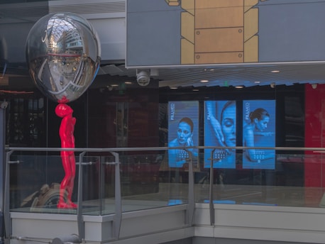 A marble statue pointing towards vibrant digital ads floating in a violet and white background.